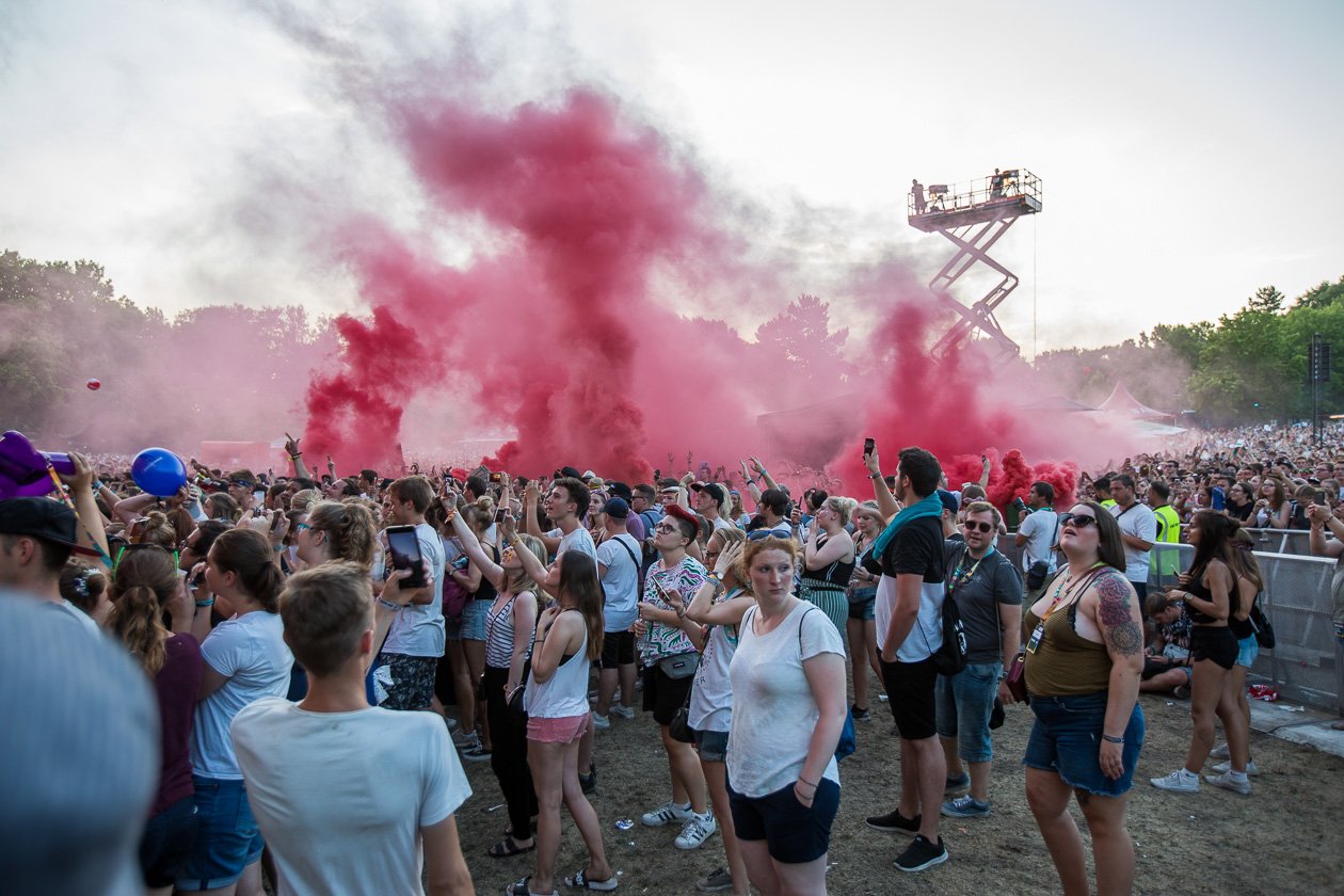 Zehntausende Fans feiern bei brütender Hitze Kraftklub u.a. – Roter Rauch über dem Gelände.