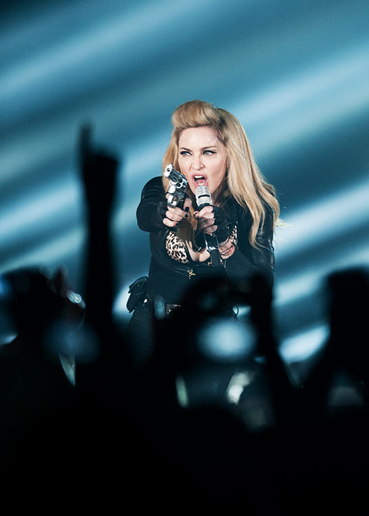 Madonna kommt, und die Massen ticken aus. Vor allem, weil sie ewig auf sich warten ließ. – Gut durchtrainierte Frau auf der Bühne