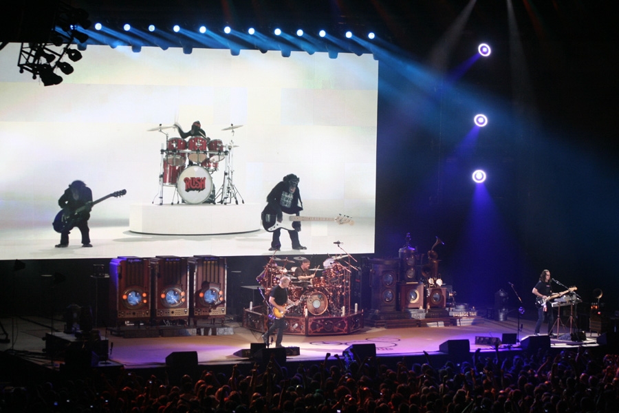 Rush – Das Trio beim einzigen Deutschland-Gig der Time Machine-Tour. – Albernheiten auf der Videoleinwand.
